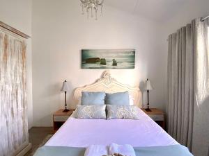 a bedroom with a white bed and a chandelier at Windekind in Struisbaai