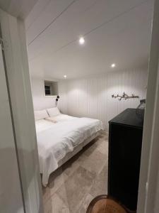 um quarto com uma cama branca e uma cómoda preta em Nyrenoverad pärla centralt i Kungshamn em Kungshamn