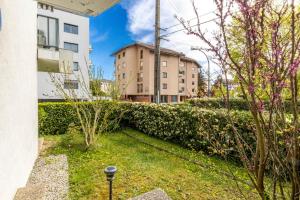 un jardin avec une haie et des bâtiments en arrière-plan dans l'établissement Le Gouverneur, 100m du lac avec parking, à Annecy
