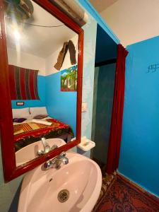 a bathroom with a sink and a mirror and a bed at Maison d'hôte Riad Todra in Tinerhir