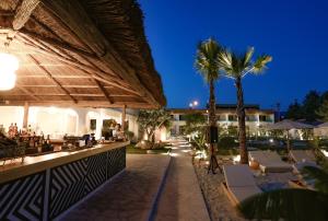 a resort with a bar and palm trees at night at Glenn Hotel & Beach in Ayvacık