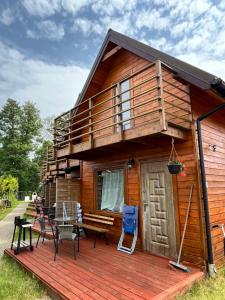 a cabin with a deck with a table and chairs at Bulisar - Domki Sarbinowo in Sarbinowo