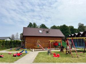a playground with play equipment in front of a house at Bulisar - Domki Sarbinowo in Sarbinowo