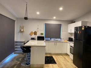 a kitchen with white cabinets and a black refrigerator at Coastal Hideaway By Lake in Toukley