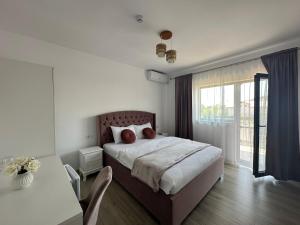 a bedroom with a bed and a large window at Vila Bloom in Vama Veche