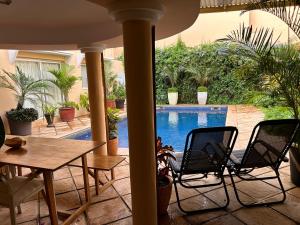 a patio with a table and chairs and a swimming pool at Two bedroom villa with private swimming pool and garden in Almadies in Dakar