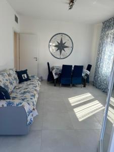 a living room with a couch and chairs and a clock at Bilocale completamente rinnovato a 100 metri dal mare con giardino in Marina di Massa
