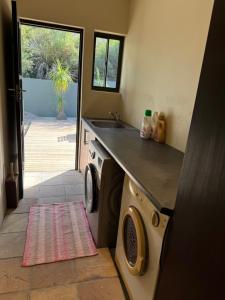 a kitchen with a sink and a washing machine at Villa Silver Vos in Hermanus