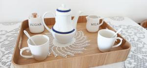 a tray with cups and mugs on a bed at M & A Ionian Balcony in Himare