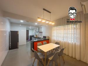 クチンにあるStaycation Homestay 51 Luxe Garden Homestayのテーブルと椅子のあるキッチンとダイニングルーム