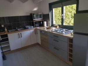 a small kitchen with a stove and a microwave at Chalet cosy in Condé-Folie