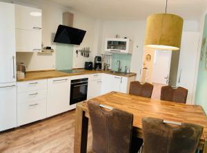 a kitchen with a wooden table and white cabinets at Tohuus1875 in Warendorf