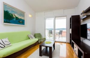 a living room with a green couch and a television at Apartment Mia - Spacious apartment on 85 m2 with beautiful sea view in Trogir