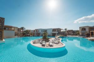 a large swimming pool with chairs and tables at Ostria Resort & Spa in Ierapetra
