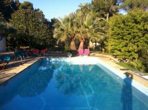 a blue swimming pool with chairs and trees at Du Coté de Chez Soi in La Ciotat