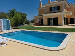 a swimming pool in front of a house at Casa dos Ventos in Olhão