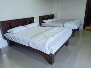 2 letti in una camera da letto con lenzuola e cuscini bianchi di Govinda Krishna Comforts a Mysore