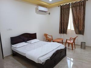 una camera da letto con un letto, due sedie e una finestra di Govinda Krishna Comforts a Mysore