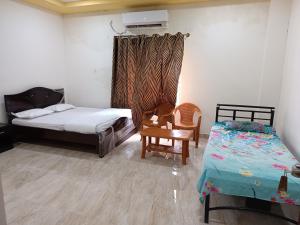 una camera da letto con due letti, un tavolo e una sedia di Govinda Krishna Comforts a Mysore