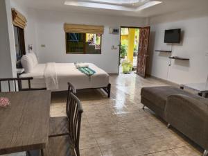 a hotel room with a bed and a couch and a table at Phratamnak Inn guesthouse - 100 mtr from the beach in Pattaya South