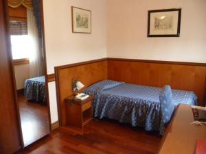 a bedroom with a blue bed and a mirror at Hotel Minerva in Pordenone