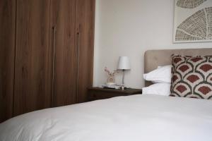 a bedroom with a white bed and a wooden cabinet at Urban Oasis Retreat in Midrand +22 photos