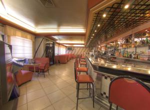 a restaurant with a bar with red chairs and tables at Hotel Avenida in Beas de Segura