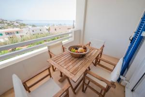a table with chairs and a bowl of fruit on a balcony at Ven al Mar in Azolimnos Syros