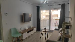 ein Wohnzimmer mit einem Sofa und einem Fernseher an der Wand in der Unterkunft Marina Golden Choice - Piso nuevo a 350m playa in Oropesa del Mar