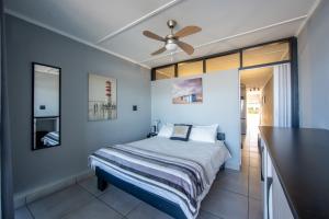 una camera con letto e ventilatore a soffitto di Driftsands Uvongo Beachfront a Uvongo Beach