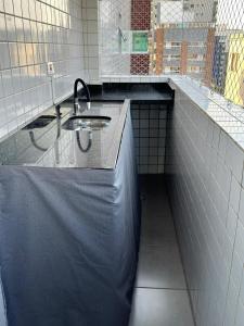 a bathroom with a sink and a tiled wall at Apartamento Vista Mar 71 in Praia Grande