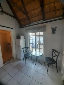 a kitchen with a table and chairs and a refrigerator at Rosewood Cottage Apartment in Himeville