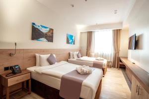 una camera d'albergo con due letti e una televisione di Kyriad Muscat a Mascate