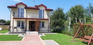 a house with a balcony and a yard at Dom letniskowy - do 10 osób in Dźwirzyno