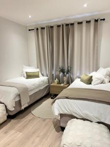 Un dormitorio con dos camas y una ventana con cortinas. en Sage Serenity Retreat, en Ciudad del Cabo