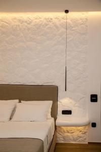 sypialnia z 2 łóżkami i białą ścianą w obiekcie Levantes Luxury Suites II w mieście Tinos