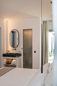 sypialnia z białym łóżkiem i lustrem w obiekcie Levantes Luxury Suites II w mieście Tinos