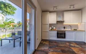 kuchnia z białymi szafkami oraz patio ze stołem w obiekcie Pet Friendly Apartment In Madulin w Medulinie