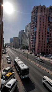 a bus driving down a city street with parked cars at Offer if booked at least 1 week Elegance Modern 1-Bedroom Close to Everything in Ajman 