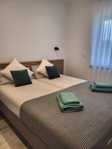 2 Betten mit grünen Handtüchern darüber in der Unterkunft Apartman Tanja & Apartman Tea in Galižana