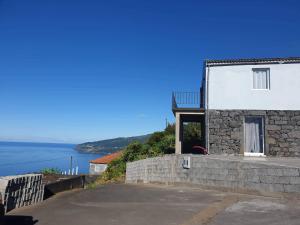a house on a hill with the ocean in the background at Vigia dos Machados in Lajes do Pico