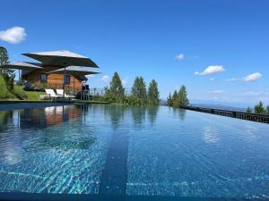 une piscine avec une maison en arrière-plan dans l'établissement Tomtegl-Bergchalet-No-2-mit-Privatsauna-Infinitypool-Kamin-Fitnessraum-1500m-Seehoehe, à Hochrindl