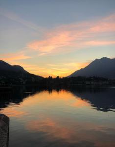 un tramonto su un lago con montagne sullo sfondo di Appartamento centrale Housitaly a Lecco