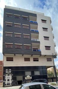 un grand bâtiment avec des voitures garées devant dans l'établissement Résidence MIMOUNA FAMILY, à Tanger