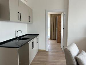 a kitchen with white cabinets and a sink and a hallway at Petra Port in Tuzla