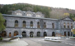 a large stone building with a car parked in front at Studio MARMOTTES au RDC a HYPER centre du Mont DORE in Mont-Dore
