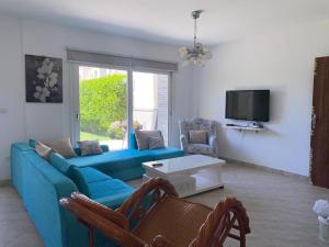 a living room with a blue couch and a tv at Duplex with Garden in Amwaj Sidi Abdel-Rahman-Beach & Pool Passes Included! in El Alamein
