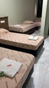 three beds in a room with pink and brown sheets at Hotelmatarazzo in Sao Paulo