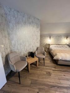 a bedroom with a bed and two chairs and a table at L'envie d'ailleurs in Malmedy