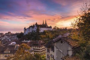 a city with a castle on a hill at sunset at Appartement thématique Art Moderne in Travers